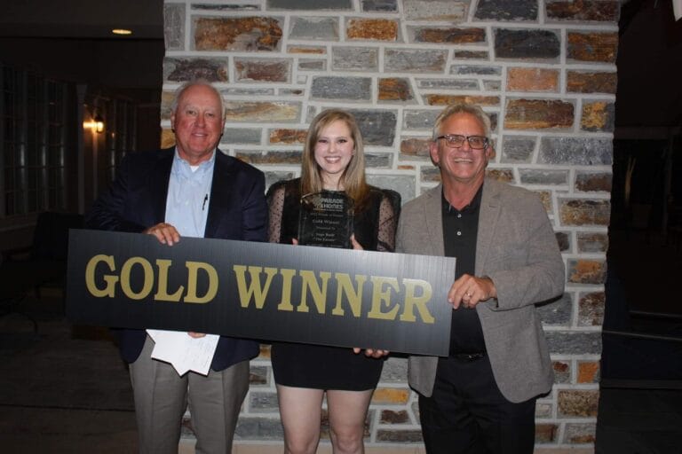 three people holding a sign that says gold winner