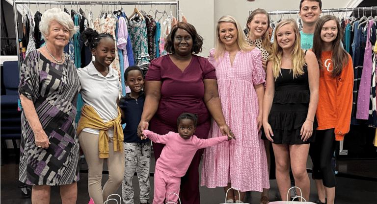 group photo of women and children in front of clothing racks